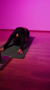 Bilgisayarla yoga yapan genç bir kadın..