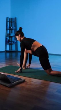 Bilgisayarla yoga yapan genç bir kadın..