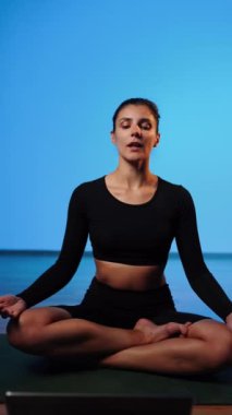 Bilgisayarla yoga yapan genç bir kadın..