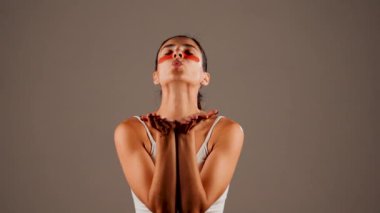 Mükemmel parıldayan derisi ve kameraya poz veren doğal makyajlı genç bir kadın. Gözlerinin altında yorgunluk ve şişkinliği azaltmak için kolajen bantları var. Deri bakımı. Modern güzellik aletleri konsepti 4k.