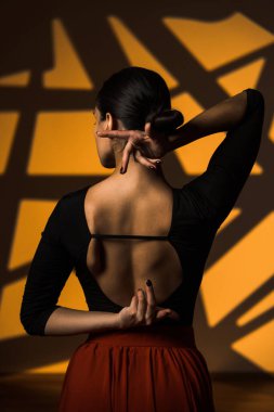 A dancing woman poses against the backdrop of illumination of gobo masks in the background. A woman dances a Spanish dance. Choreography and dance concept clipart