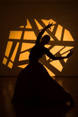 Dansçı bir kadın arka planda gobo maskelerin aydınlatılmasına karşı poz veriyor. Bir kadın İspanyol dansı yapıyor. Koreografi ve dans konsepti