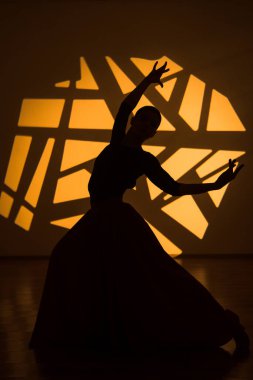 Dansçı bir kadın arka planda gobo maskelerin aydınlatılmasına karşı poz veriyor. Bir kadın İspanyol dansı yapıyor. Koreografi ve dans konsepti