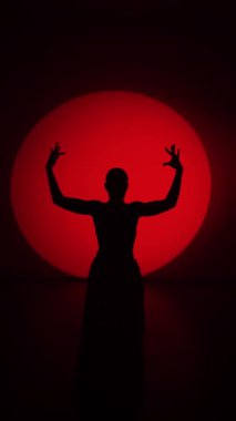 Kırmızı etekli bir kadının silueti neon ışıkta Latince dans ediyor. Dans konsepti. Bachata, Flamenko. Latino. Rumba. Samba.Dikey video 4k