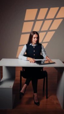 Stüdyoda dizüstü bilgisayarda çalışan genç bir kadın. Çevrimiçi iş kavramı. İnternette çalışan bir kadının portresi. Dikey video