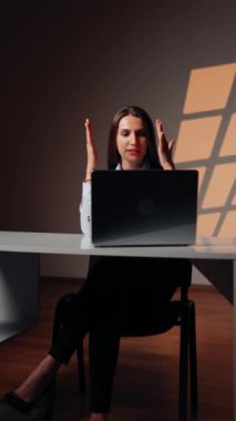 Stüdyoda dizüstü bilgisayarda çalışan genç bir kadın. Çevrimiçi iş kavramı. İnternette çalışan bir kadının portresi. Dikey video