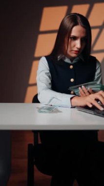 Bir kadın finansör dizüstü bilgisayarda çalışırken kârı sayar. Bir kadın para sayar. İş konsepti. Dikey video