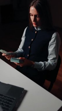 Bir kadın finansör dizüstü bilgisayarda çalışırken kârı sayar. Bir kadın para sayar. İş konsepti. Dikey video