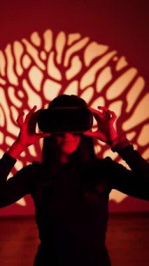 Bir kadın sanal gerçeklik dünyasının tadını VR gözlükleriyle çıkarır. Sanal gerçeklik kulaklığı. Yapay zeka. VR gözlük konsepti. Dikey video 4k
