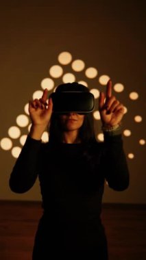 Bir kadın sanal gerçeklik dünyasının tadını VR gözlükleriyle çıkarır. Sanal gerçeklik kulaklığı. Yapay zeka. VR gözlük konsepti. Dikey video 4k