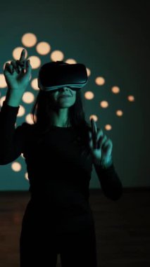 Bir kadın sanal gerçeklik dünyasının tadını VR gözlükleriyle çıkarır. Sanal gerçeklik kulaklığı. Yapay zeka. VR gözlük konsepti. Dikey video 4k