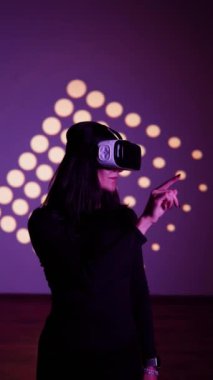 Bir kadın sanal gerçeklik dünyasının tadını VR gözlükleriyle çıkarır. Sanal gerçeklik kulaklığı. Yapay zeka. VR gözlük konsepti. Dikey video 4k