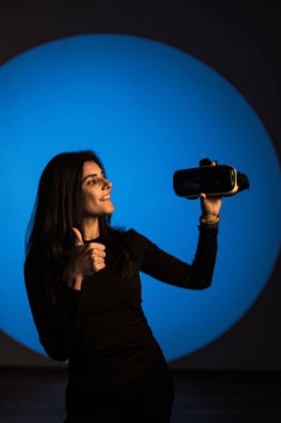 Bir kadın sanal gerçeklik dünyasının tadını VR gözlükleriyle çıkarır. Sanal gerçeklik kulaklığı. Yapay zeka. VR gözlük konsepti. Dikey fotoğraf