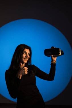 Bir kadın sanal gerçeklik dünyasının tadını VR gözlükleriyle çıkarır. Sanal gerçeklik kulaklığı. Yapay zeka. VR gözlük konsepti. Dikey fotoğraf