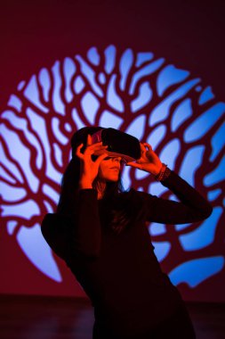 Bir kadın sanal gerçeklik dünyasının tadını VR gözlükleriyle çıkarır. Sanal gerçeklik kulaklığı. Yapay zeka. VR gözlük konsepti. Dikey fotoğraf