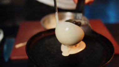 Aşçı kızartma tavasında krep pişirir. Krepleri ateşte pişirmek. Tatlı yemek kavramı 4K