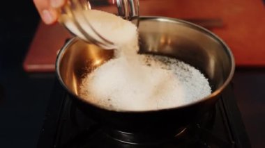 Aşçı tavada şeker eriterek tatlı karamel hazırlar. Karamel yapma süreci. Tatlı konsepti.