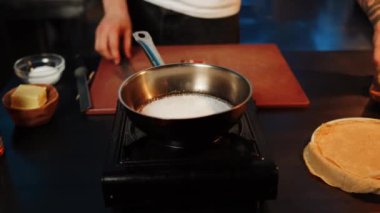 Aşçı tavada şeker eriterek tatlı karamel hazırlar. Karamel yapma süreci. Tatlı konsepti.