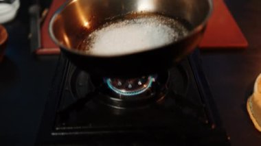 Aşçı tavada şeker eriterek tatlı karamel hazırlar. Karamel yapma süreci. Tatlı konsepti.