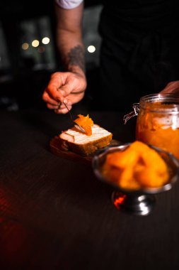 Kavanozda balkabağı reçeli. Ekmeğe yayılmış kabak reçeli. Aşçı balkabağı reçeli hazırlar. Siyah arkaplanda balkabağı reçeli