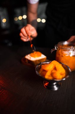 Kavanozda balkabağı reçeli. Ekmeğe yayılmış kabak reçeli. Aşçı balkabağı reçeli hazırlar. Siyah arkaplanda balkabağı reçeli