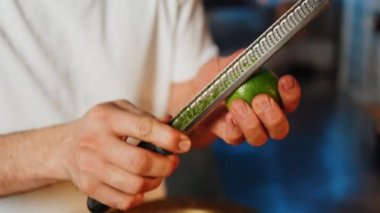 Bir şekerci limon, limon ve portakal kabuklarını rendeliyor. Turunçgil lezzeti üretimi. Şekerleme ürünleri kavramı
