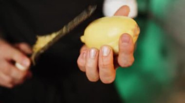 Bir şekerci limon, limon ve portakal kabuklarını rendeliyor. Turunçgil lezzeti üretimi. Şekerleme ürünleri kavramı