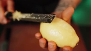 Bir şekerci limon, limon ve portakal kabuklarını rendeliyor. Turunçgil lezzeti üretimi. Şekerleme ürünleri kavramı