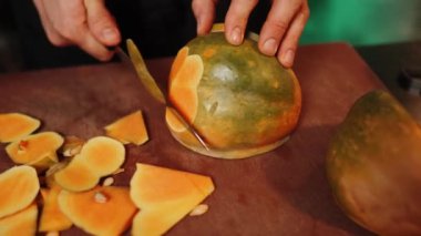 Aşçı olgun bir portakal kabağını keser. Balkabağı tabağı. Sonbahar yemekleri konsepti 4k