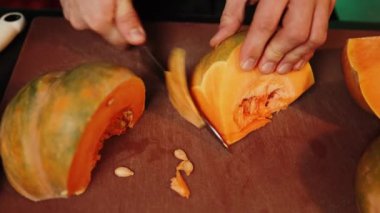 Aşçı olgun bir portakal kabağını keser. Balkabağı tabağı. Sonbahar yemekleri konsepti 4k