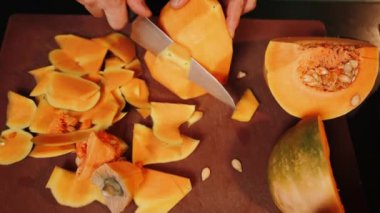 Aşçı olgun bir portakal kabağını keser. Balkabağı tabağı. Sonbahar yemekleri konsepti 4k