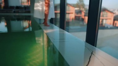 Genç bir kadın dağ manzaralı bir havuzda yüzüyor. Bir kadın kaplıcada dinlenmekten hoşlanır. Otel tatili konsepti 4k