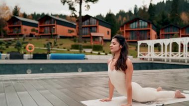Spor yapan bir kadın bulutlu bir havada terasta dağların arka planında yoga yapıyor. Yoga ve meditasyon. Asanas. Manevi gelişim kavramı