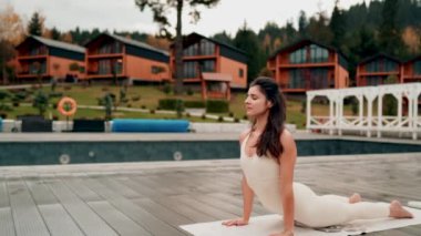 Spor yapan bir kadın bulutlu bir havada terasta dağların arka planında yoga yapıyor. Yoga ve meditasyon. Asanas. Manevi gelişim kavramı