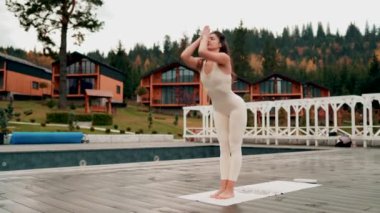 Spor yapan bir kadın bulutlu bir havada terasta dağların arka planında yoga yapıyor. Yoga ve meditasyon. Asanas. Manevi gelişim kavramı