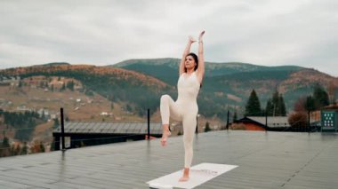 Spor yapan bir kadın bulutlu bir havada terasta dağların arka planında yoga yapıyor. Yoga ve meditasyon. Asanas. Manevi gelişim kavramı