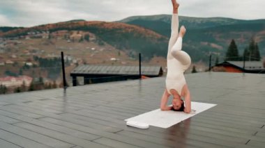 Spor yapan bir kadın bulutlu bir havada terasta dağların arka planında yoga yapıyor. Yoga ve meditasyon. Asanas. Manevi gelişim kavramı