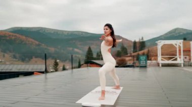 Spor yapan bir kadın bulutlu bir havada terasta dağların arka planında yoga yapıyor. Yoga ve meditasyon. Asanas. Manevi gelişim kavramı