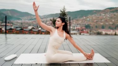 Spor yapan bir kadın bulutlu bir havada terasta dağların arka planında yoga yapıyor. Yoga ve meditasyon. Asanas. Manevi gelişim kavramı