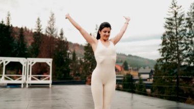 Spor yapan bir kadın bulutlu bir havada terasta dağların arka planında yoga yapıyor. Yoga ve meditasyon. Asanas. Manevi gelişim kavramı