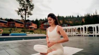 Spor yapan bir kadın bulutlu bir havada terasta dağların arka planında yoga yapıyor. Yoga ve meditasyon. Asanas. Manevi gelişim kavramı