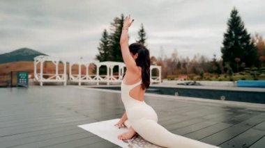 Spor yapan bir kadın bulutlu bir havada terasta dağların arka planında yoga yapıyor. Yoga ve meditasyon. Asanas. Manevi gelişim kavramı