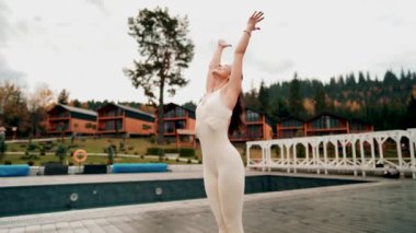 Spor yapan bir kadın bulutlu bir havada terasta dağların arka planında yoga yapıyor. Yoga ve meditasyon. Asanas. Manevi gelişim kavramı