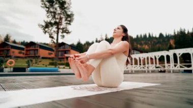 Spor yapan bir kadın bulutlu bir havada terasta dağların arka planında yoga yapıyor. Yoga ve meditasyon. Asanas. Manevi gelişim kavramı