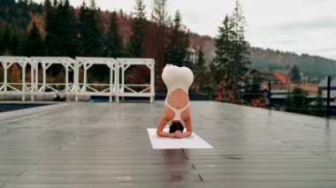 Spor yapan bir kadın bulutlu bir havada terasta dağların arka planında yoga yapıyor. Yoga ve meditasyon. Asanas. Manevi gelişim kavramı