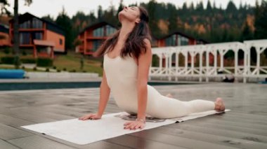 Spor yapan bir kadın bulutlu bir havada terasta dağların arka planında yoga yapıyor. Yoga ve meditasyon. Asanas. Manevi gelişim kavramı