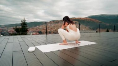 Spor yapan bir kadın bulutlu bir havada terasta dağların arka planında yoga yapıyor. Yoga ve meditasyon. Asanas. Manevi gelişim kavramı