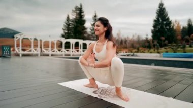 Spor yapan bir kadın bulutlu bir havada terasta dağların arka planında yoga yapıyor. Yoga ve meditasyon. Asanas. Manevi gelişim kavramı