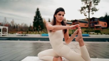 Spor yapan bir kadın bulutlu bir havada terasta dağların arka planında yoga yapıyor. Yoga ve meditasyon. Asanas. Manevi gelişim kavramı