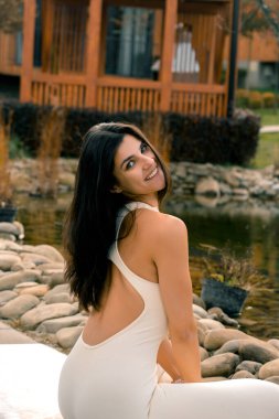 Beyaz takım elbiseli genç bir kadın dağdaki bir evin yakınında yoga yapıyor. Dağlarda meditasyon yapan bir kadın. Yoga ve meditasyon kavramı. Asanas